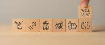 Employee wellbeing concept. Wooden blocks with physical, mental, emotional health icons. Creating employee benefits, satisfaction programs. Fostering positive work culture, employee engagement.